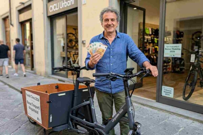 Bonus Mobilità 2026: uomo mostra banconote euro dopo l'acquisto di una cargo bike elettrica con gli incentivi del Fondo Clima davanti a un negozio di biciclette.