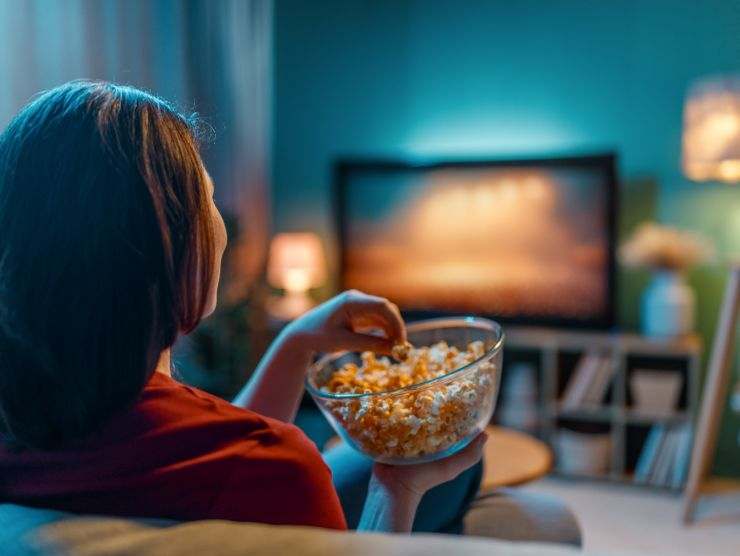 donna che guarda la tv e mangia popcorn