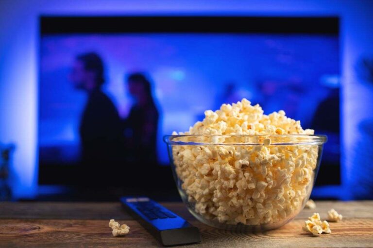 tv accesa in cui si vede un film in onda e ciotola con popcorn