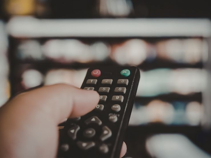 persona che usa telecomando per cambiare canale